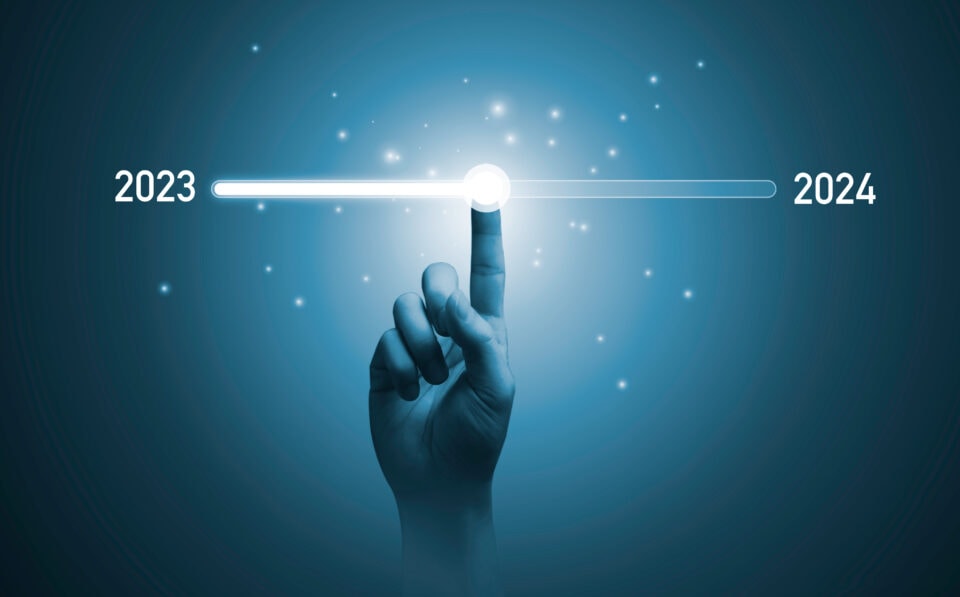 A hand is pointing to the year 2023 on a blue background.