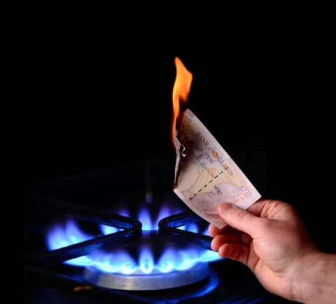 A hand holding a piece of paper on a gas stove.